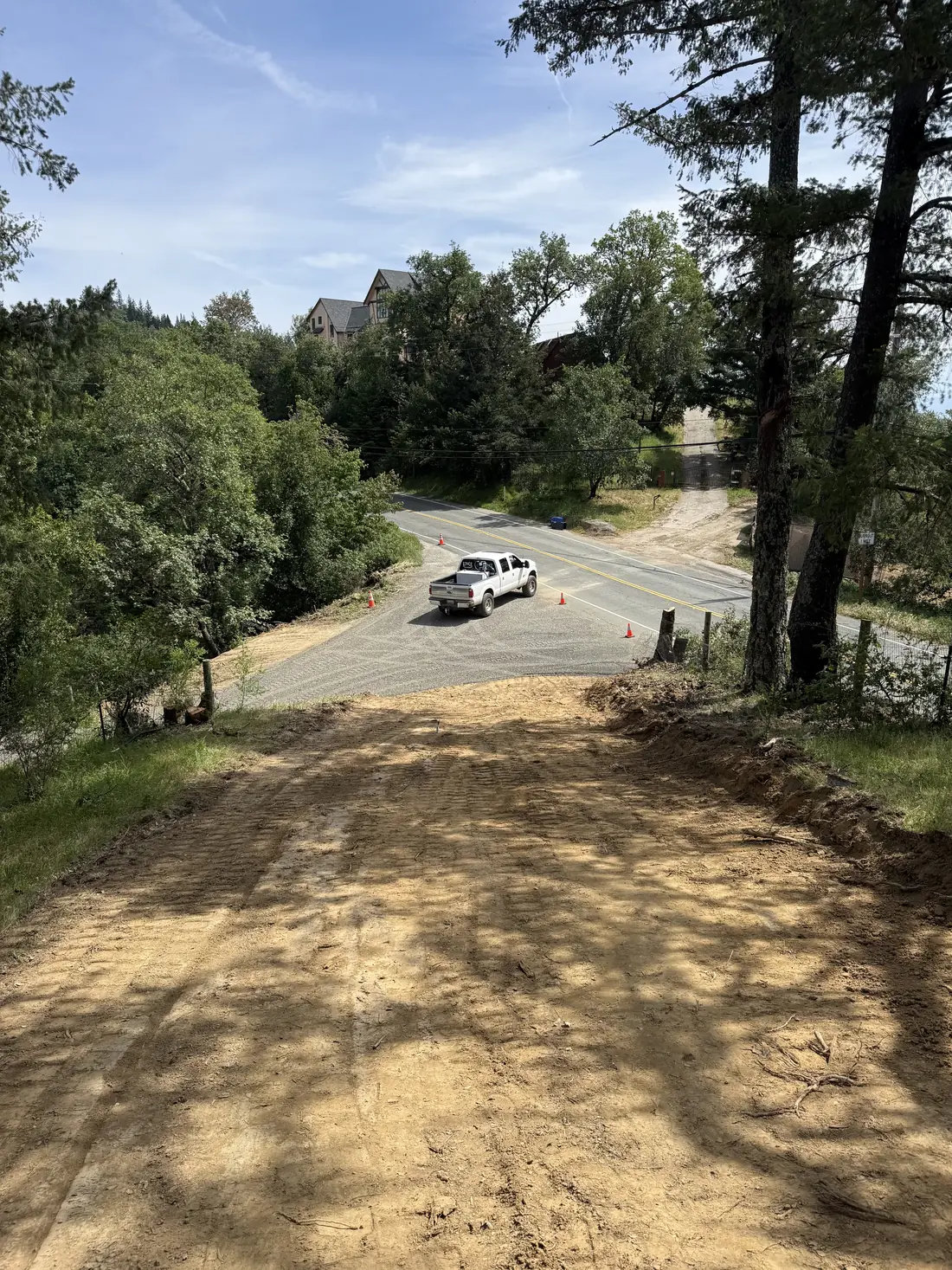 Freshly graded downhill driveway connecting to the road below