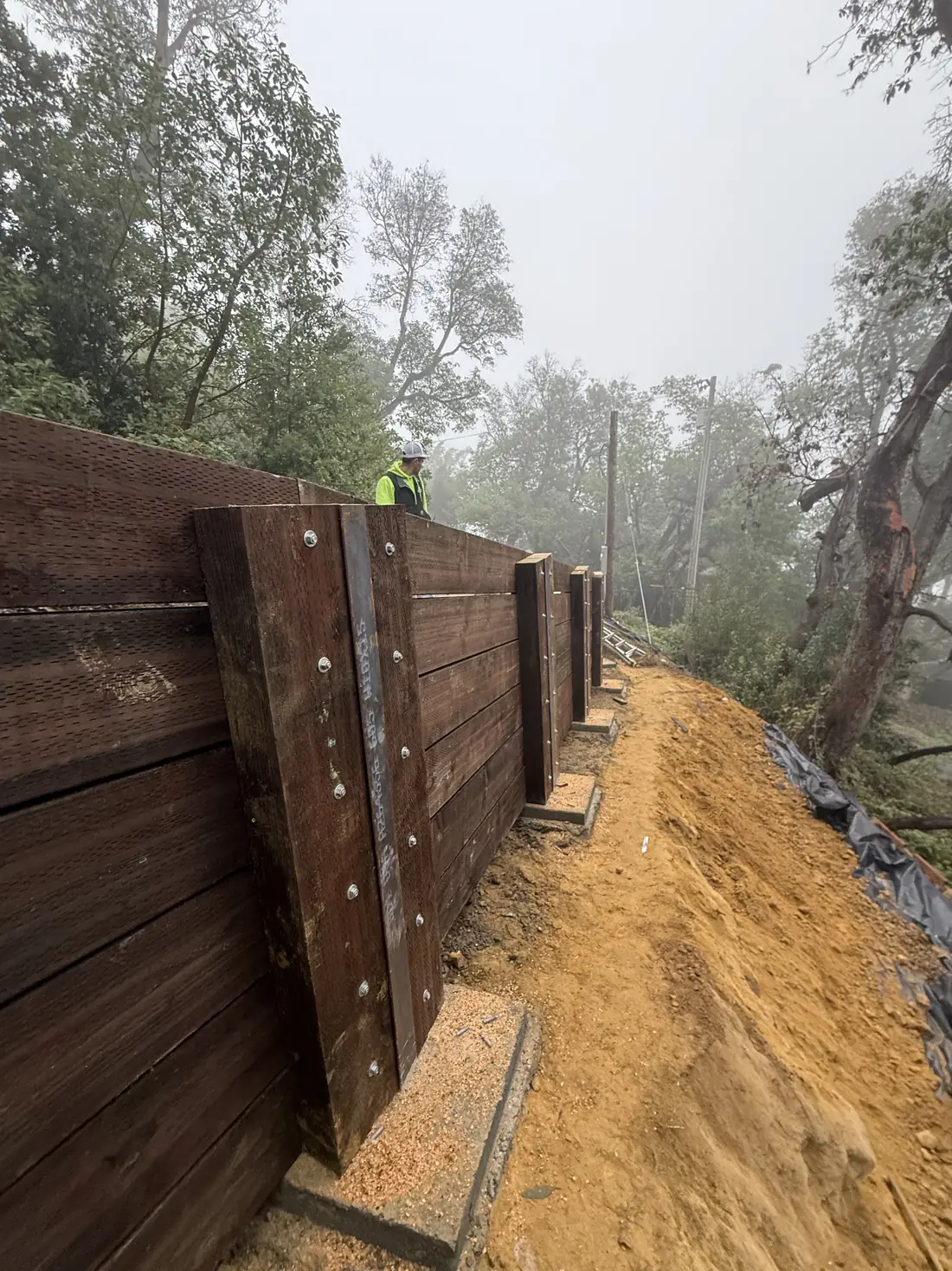 Wood lag retaining wall along a cut slope in the fog