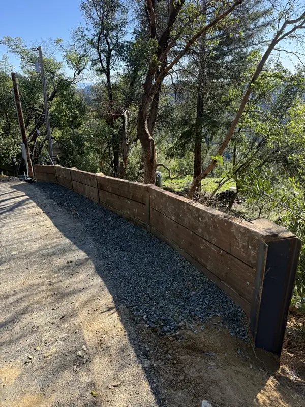 Completed wood lag retaining wall along the gravel road