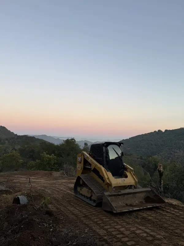 Skid steer on a freshly cleared and graded ridgetop at sunset